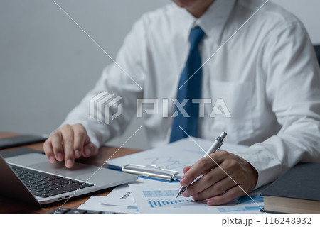businessman holding pen to analyze data, graphs and market reports of business and growth trends. businessman holding pen to analyze data, graphs and market reports of business and growth trends. 116248932