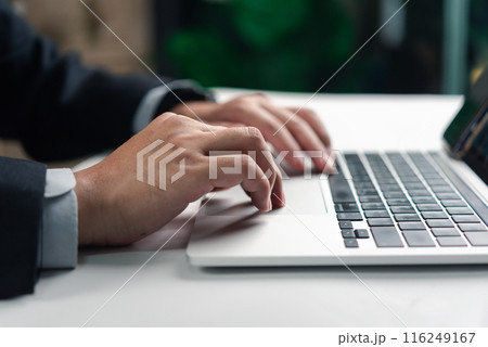 Business professional working on a laptop, focused on task with blurred green background 116249167