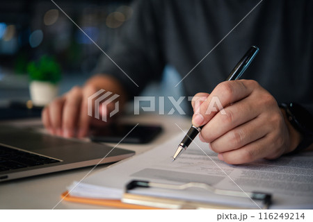 A businessman's hands with a pen over documents, analysis at the workplace. A businessman's hands with a pen over documents, analysis at the workplace. 116249214