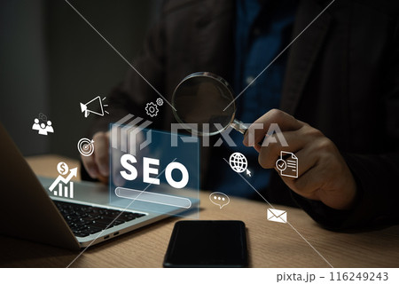 A man is looking at a laptop with a magnifying glass on it 116249243