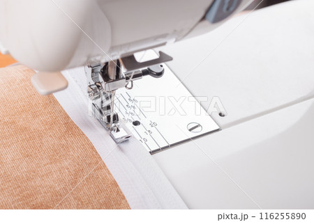 Modern sewing machine special presser foot with beige fabric and zipper, closeup 116255890