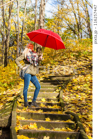 Woman walking in park with umbrella 116257447