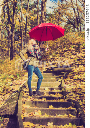Woman walking in park with umbrella 116257448