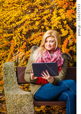 Woman relaxing sitting on bench in park using tablet Woman relaxing sitting on bench in park using tablet 116257553