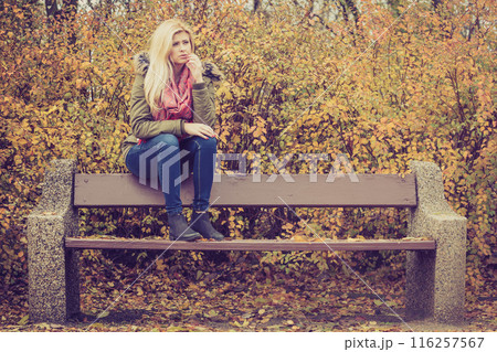 Woman relaxing sitting on bench in autumnal park Woman relaxing sitting on bench in autumnal park 116257567