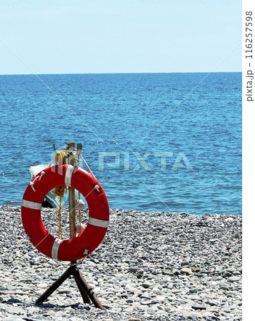 Lifebuoy on the seashore. Beach safety equipment. Positioned by water s edge for emergencies and rescue purposes Lifebuoy on the seashore. Beach safety equipment. Positioned by water s edge for emergencies and rescue purposes 116257598