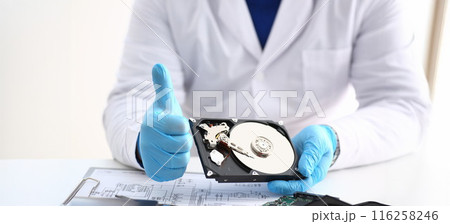 Man in uniform hold disassembled hard drive from computer, hdd and reader, show thumbs up 116258246