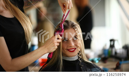 Blonde female on hairdresser appointment, master create curly hairstyle Blonde female on hairdresser appointment, master create curly hairstyle 116258974