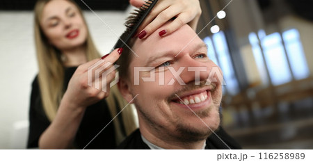 Female professional hairdresser cutting hair with scissors, smiling male client sit in masters chair Female professional hairdresser cutting hair with scissors, smiling male client sit in masters chair 116258989