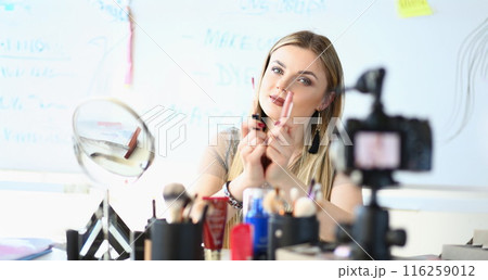Pretty young woman wear makeup, glamour blonde woman visagist show lipstick on camera 116259012