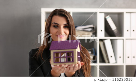 Woman realtor hold miniature toy house in hand, symbol for real estate 116259019