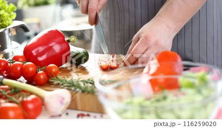 Male chef cutting hot pepper with sharp knife, veggies on cutting board, enjoy cooking 116259020