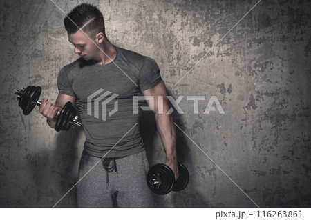 Young bodybuilder doing biceps curls with dumbbells Young bodybuilder doing biceps curls with dumbbells 116263861