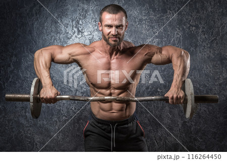 Bodybuilder man with barbell against concrete wall Bodybuilder man with barbell against concrete wall 116264450