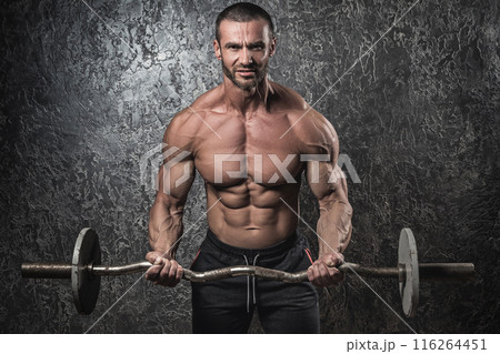 Bodybuilder man with barbell against concrete wall 116264451