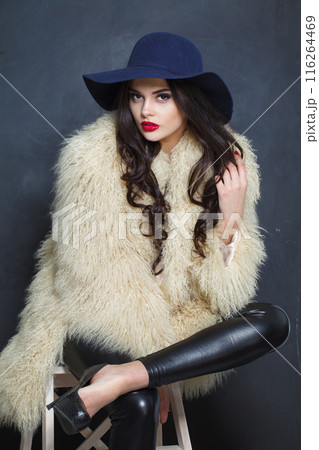 Stylish young brunette lady with makeup and long curly hair posing Stylish young brunette lady with makeup and long curly hair posing 116264469