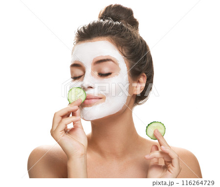 Woman with facial mask and cucumber slices in her hands 116264729