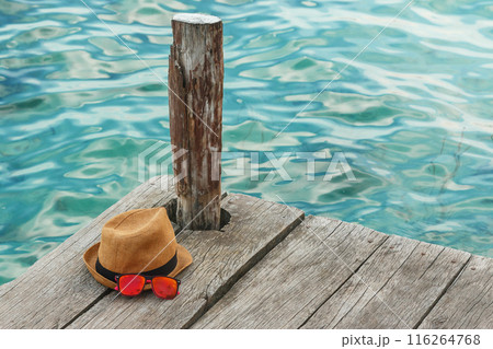 Straw hat and sunglasses on wooden pier Straw hat and sunglasses on wooden pier 116264768