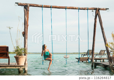 Beautiful woman on the swings which above a water 116264817