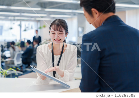 窓口で来客の対応をする女性スタッフ 116265308