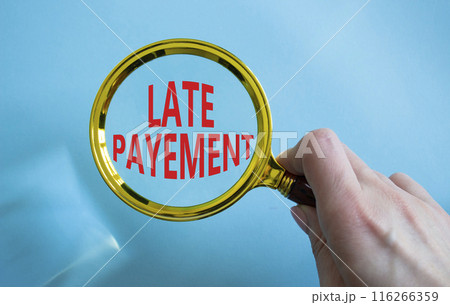 Late payment symbol. Concept word Late payment on magnifying glass. Businessman hand. Beautiful blue background. Business and Late payment concept. Copy space 116266359