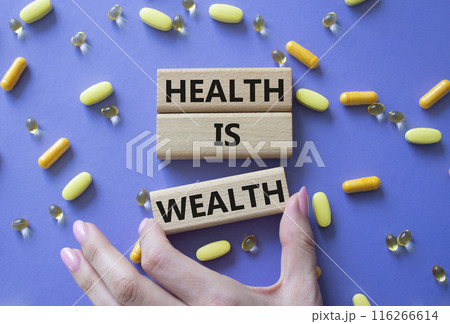Health is Wealth symbol. Concept word Health is Wealth on wooden blocks. Doctor hand. Beautiful purple background with pills. Medicine and Health is Wealth concept. Copy space Health is Wealth symbol. Concept word Health is Wealth on wooden blocks. Doctor hand. Beautiful purple background with pills. Medicine and Health is Wealth concept. Copy space 116266614