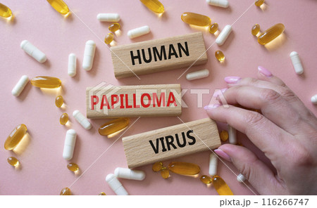 Human Papilloma Virus symbol. Concept word Human Papilloma Virus on wooden blocks. Doctor hand. Beautiful pink background with pills. Medicine and Human Papilloma Virus concept. Copy space 116266747