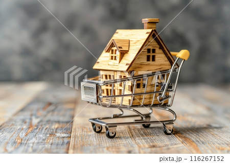 Wooden house model in a shopping cart on a wooden surface. Real estate and home buying concept. 116267152