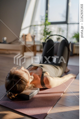 A woman is using a hip Magic Circle at Glute bridge Pilates workout in studio, being active and committed to exercising 116269168