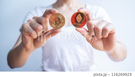 Cropped shot of woman holding a golden Bitcoin token with Ethereum coin isolated on white background. Cropped shot of woman holding a golden Bitcoin token with Ethereum coin isolated on white background. 116269929
