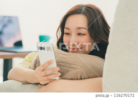 リビングのソファでスマホを操作する若い女性 リビングのソファでスマホを操作する若い女性 116270172