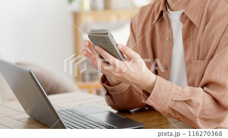 パソコンとスマートフォンを使う男性 116270368
