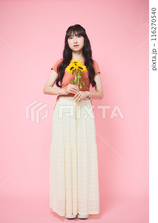 ピンク背景でヒマワリを持つ女性のポートレー ピンク背景でヒマワリを持つ女性のポートレー 116270540