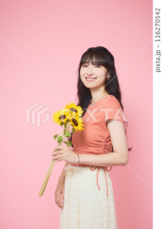 ピンク背景でヒマワリを持つ女性のポートレー ピンク背景でヒマワリを持つ女性のポートレー 116270542