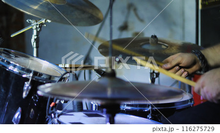 A musician passionately playing a drum kit, creating rhythmic beats and sounds. The image captures the essence of live music and performance. A musician passionately playing a drum kit, creating rhythmic beats and sounds. The image captures the essence of live music and performance. 116275729