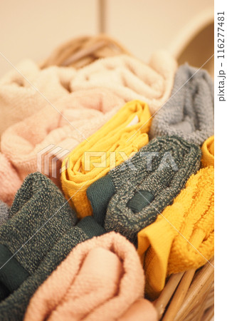 A storage basket made of wood filled with an assortment of towels 116277481