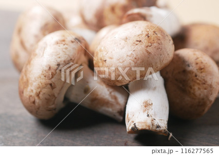 Fresh champignons mushroom in a white bowl on table  116277565