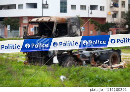 Belgian police tape in front of an arsonned truck Belgian police tape in front of an arsonned truck 116280291