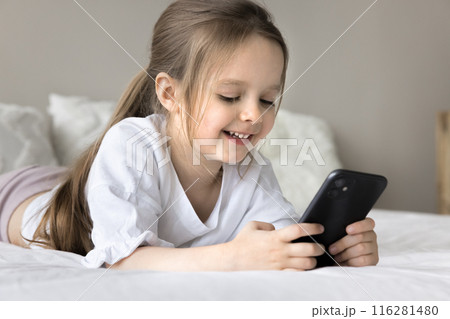Little 4s girl lies on comfy bed using modern smartphone 116281480