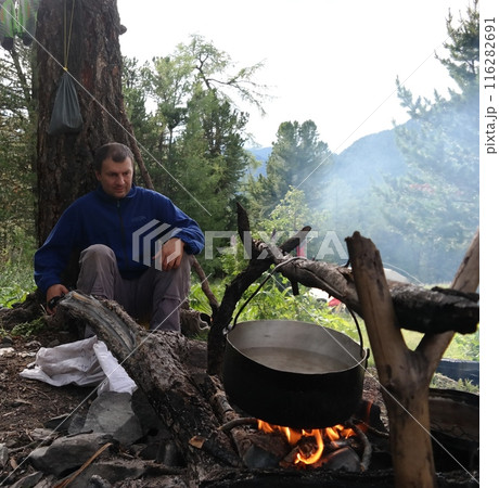 Man cooking a traditional meal over an open fire in the mountains 116282691