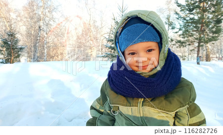 Portrait of a happy smiling child in winter clothes against a snowy background 116282726