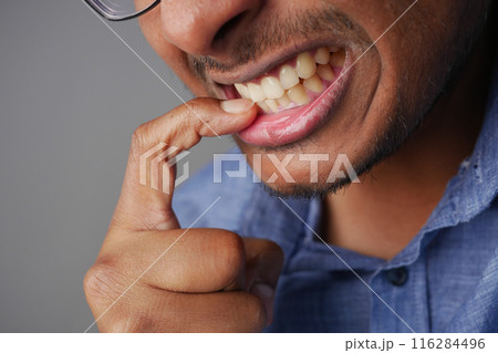 young men biting his nails at home, 116284496