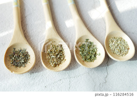 Four wooden spoons holding various spices on a table 116284516