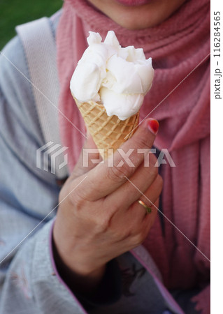 Female holds in her hand a cone with ice cream Female holds in her hand a cone with ice cream 116284565
