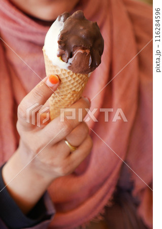 Female holds in her hand a cone with ice cream Female holds in her hand a cone with ice cream 116284596