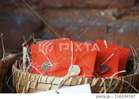 A stack of red color soaps with ribbons in a basket A stack of red color soaps with ribbons in a basket 116284597