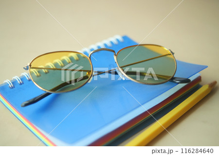 notepad, eyeglass and a pencil on wooden table notepad, eyeglass and a pencil on wooden table 116284640