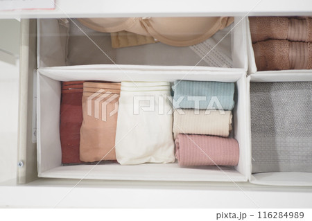 A storage basket made of wood filled with an assortment of towels A storage basket made of wood filled with an assortment of towels 116284989