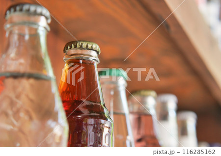 Vintage beverage bottles with colorful caps on bar shelf create a nostalgic retro drinks display Vintage beverage bottles with colorful caps on bar shelf create a nostalgic retro drinks display 116285162