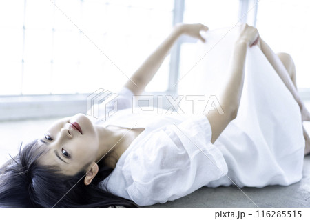 寝転ぶ白ワンピースの若い女性 116285515